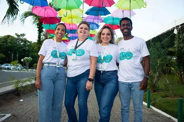 Equipe com camisetas de evento sob guarda-chuvas coloridos