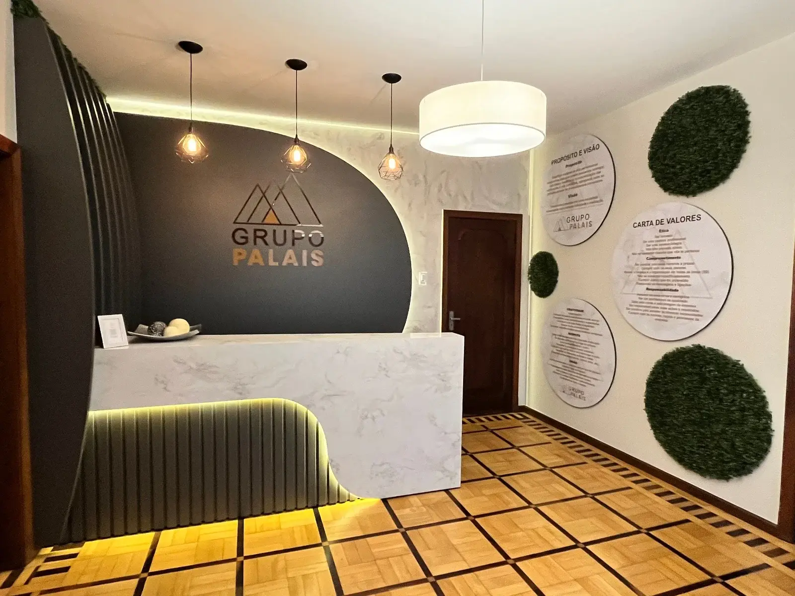 Recepção do Grupo Palais com a logo na parede escura