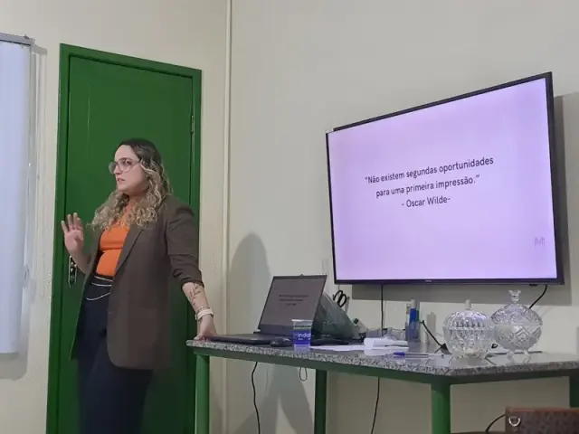 Palestrante ao lado de uma TV com citação de Oscar Wilde